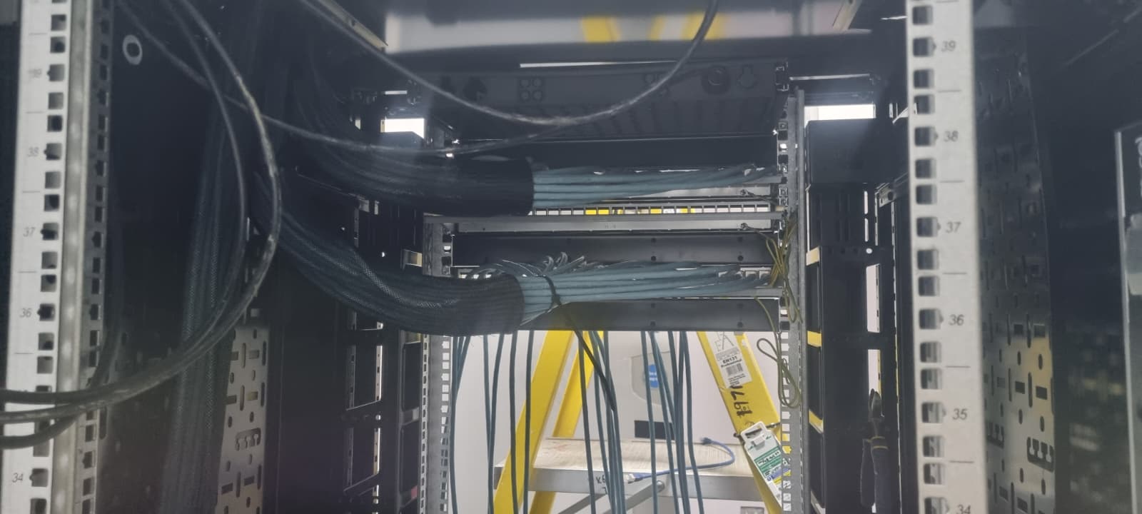 Server cabinet patching mid-installation, ladder and tools in shot